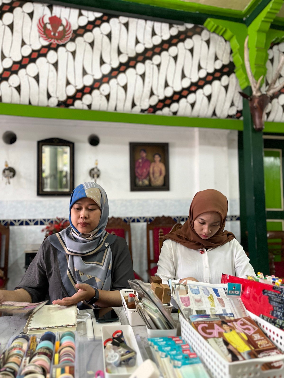 Dua peserta menulis jurnal di pendopo joglo, bahan deco tertata di meja